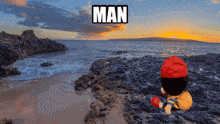 a man is sitting on a rocky beach looking out over the ocean