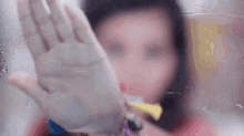 a blurry picture of a person 's face with their hand on a glass