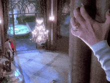 a woman 's hand with a ring on it is reaching out towards a chandelier