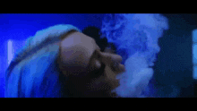 a woman with blue hair smoking a hookah in a dark room