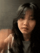 a close up of a woman 's face with long hair and bangs looking at the camera .