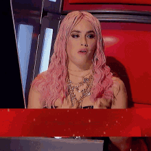 a woman with pink hair sitting in a chair