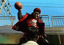 a man wearing a red jacket with raks on it holds a basketball