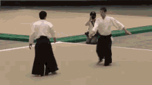 a man is taking a picture of two karate fighters on a court .