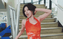 a woman in a red dress is standing in front of stairs