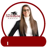 a woman wearing glasses and a white turtleneck stands in front of the biedermann group logo