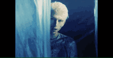 a man with white hair is looking out a window