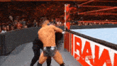 a man is wrestling another man in a wrestling ring with a sign that says raw on it .