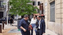 a group of people are walking down a sidewalk in front of a building with a sign that says ' pharmacie '