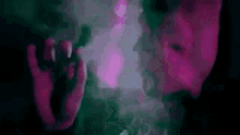a close up of a person smoking a cigarette in a dark room with smoke coming out of their mouth .