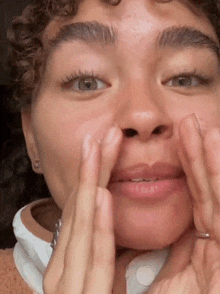 a close up of a person 's face with their hands on it