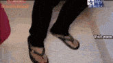 a person wearing flip flops is standing on a white tile floor .
