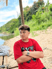 a man wearing a red t-shirt with a black cat on it stands with his arms crossed