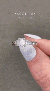 a close up of a woman 's hand with white nails and a ring on her finger