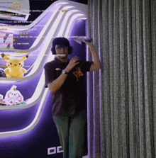 a man wearing headphones and a shirt that says ya stands in front of a purple wall
