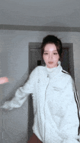 a woman wearing a white jacket is dancing in a room .
