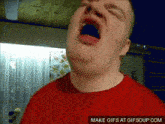 a man in a red shirt is yawning with his mouth wide open