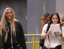 a woman wearing a black jacket with the letter r on it is smiling