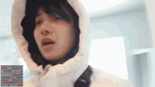 a person wearing a white jacket with a hood is looking at a screen that says ' christmas tree ' on it