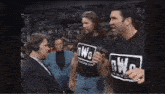 a man wearing a nwo t-shirt is talking into a microphone .