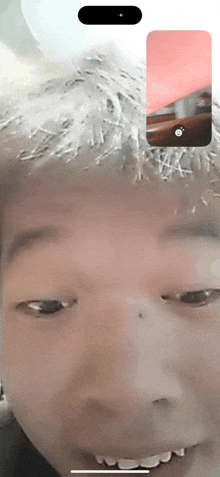 a close up of a person 's face on a phone with a green light on the bottom right