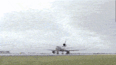 an airplane is taking off from a runway with a cloudy sky behind it