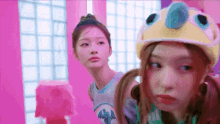 a couple of girls are standing next to each other in a pink room . one of the girls is wearing a crown .