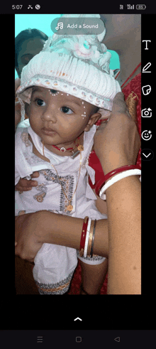 a baby wearing a white hat is being held by a woman with the add a sound button visible