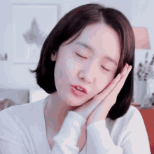 a close up of a woman sleeping with her eyes closed and her hands on her face .
