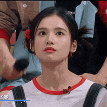 a woman with a red flower in her hair is wearing a white shirt and black overalls