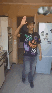 a man in a black shirt is dancing in a kitchen with his hand up .