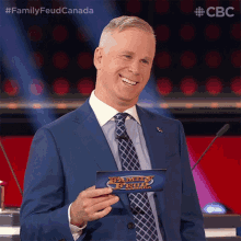a man in a suit and tie is holding a family feud card