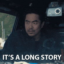 a man sitting in a car with the words it 's a long story on the bottom