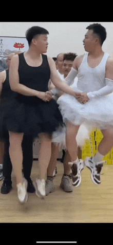 a group of men dressed as ballerinas are shaking hands in a room .