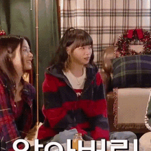 a woman in a red and black striped hoodie is sitting on a couch with two other women .