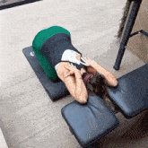 a woman is laying on a yoga mat on a bench with a black cushion