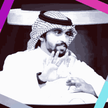 a man with a beard wearing a white shirt and a head scarf