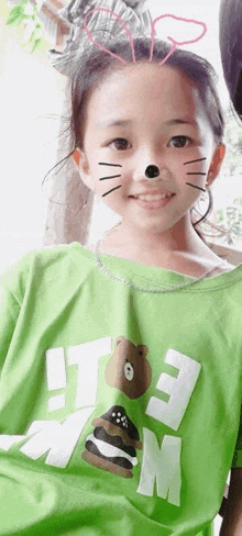 a little girl is wearing a green shirt that says i love mom