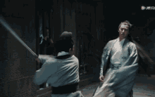 a man in a kimono is fighting another man with a sword in a dark room ..