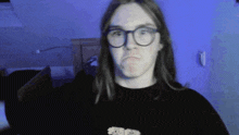 a man with long hair wearing glasses making a funny face