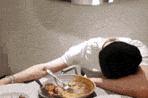 a man is sleeping at a table with a plate of food and a fork .