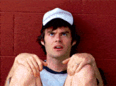 a man wearing a baseball cap and a ring sits on the ground