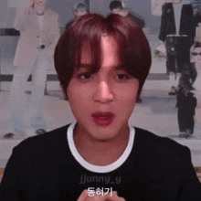 a young man with red hair is making a funny face in front of a wall with pictures of people .