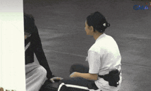 a woman in a white shirt sits on the ground next to a man in a black shirt with the word property on it