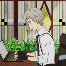 a man is typing on a laptop with a stained glass window behind him