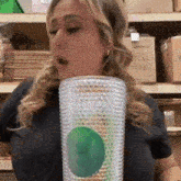 a woman in a black shirt is holding a cup with a green apple on it