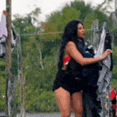 a woman in a bikini is standing next to a clothesline holding a bunch of clothes .