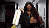 a woman in a black jacket is holding a white bag and a yellow tape measure
