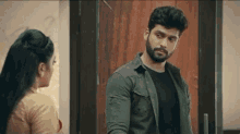 a man with a beard and a woman are standing next to each other in front of a door .
