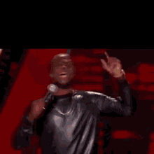 a man in a leather jacket is holding a microphone and singing into it on a stage .